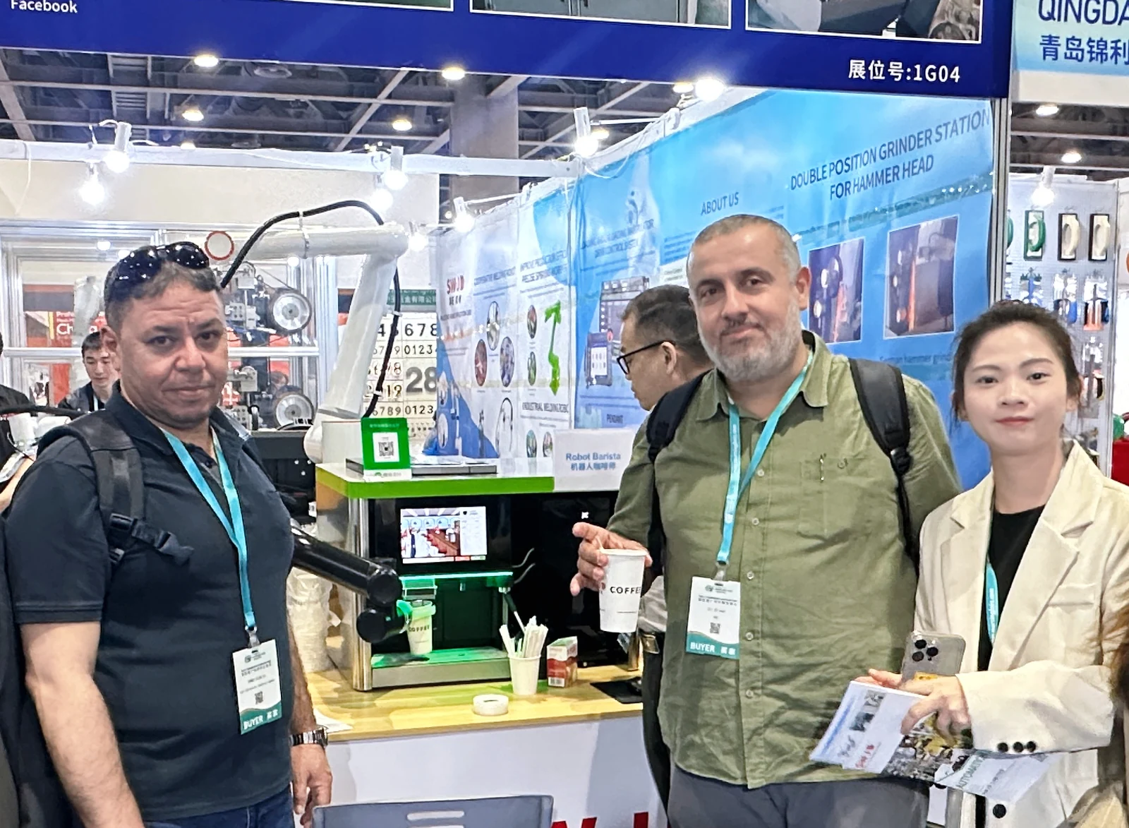 Visitors and a team member beside a robotic coffee station, with one visitor holding a cup of coffee