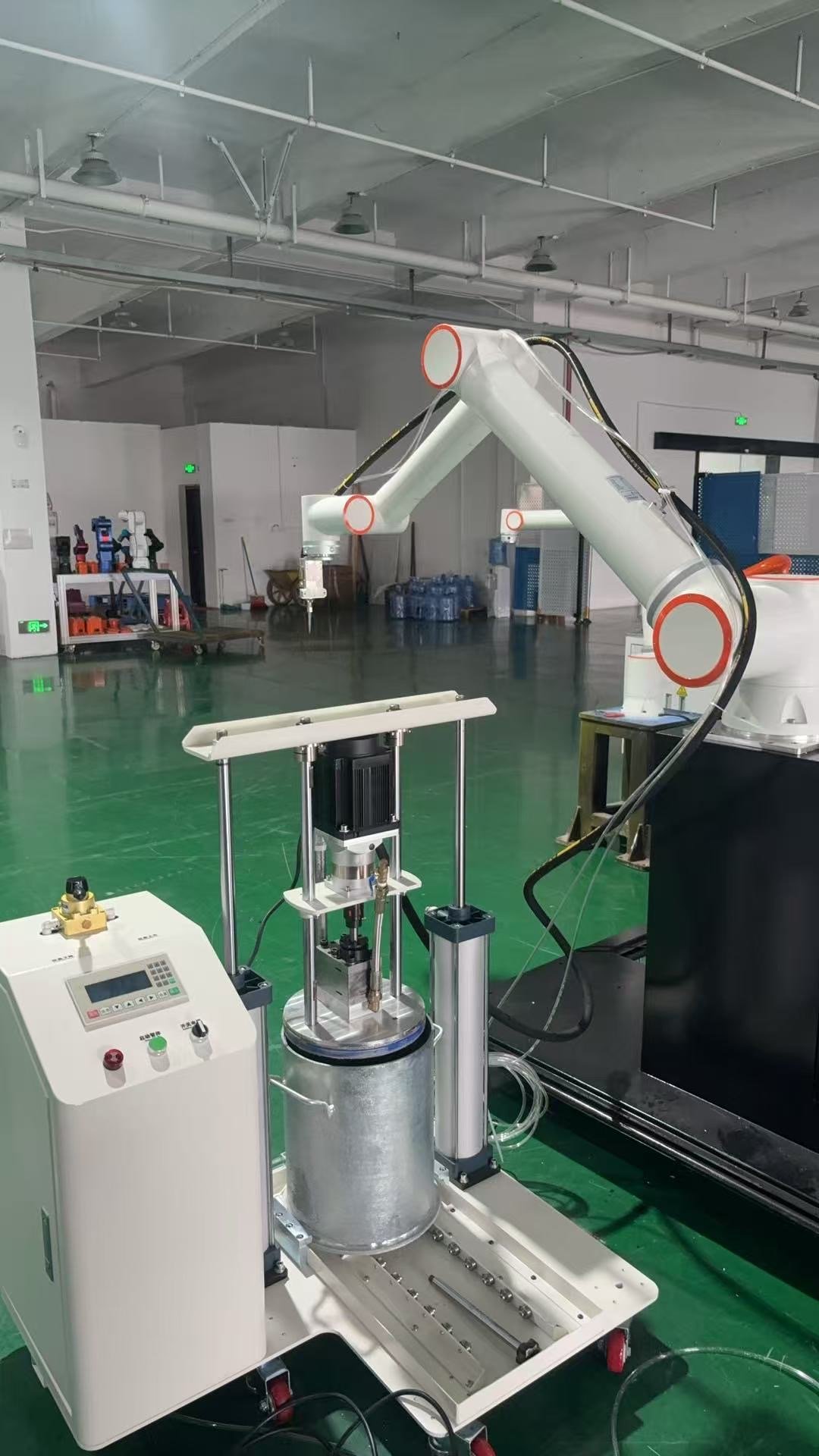 Front three-quarter view of the adhesive dispensing robot with its supply pump and control cabinet