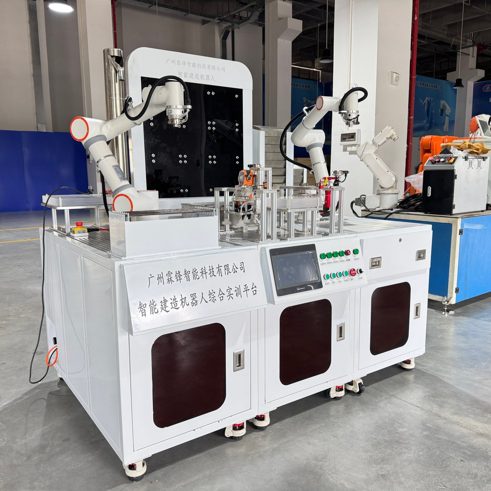 Angled view of the training workstation, robot arms and control cabinet